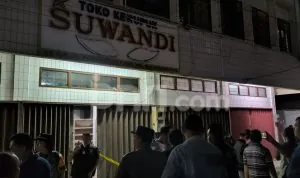 Suasana depan Toko Kerupuk Suwandi di kawasan 15 Ilir Palembang tampak dipadati warga dan aparat kepolisian saat proses olah TKP pasca dugaan perampokan sadis yang menewaskan pemilik toko, pada hari Selasa malam, tanggal 26 November 2025. Polisi memasang garis pembatas untuk mengamankan lokasi kejadian.