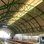 Suasana peron Stasiun LRT Sumsel yang bersih dengan satu unit kereta LRT sedang berhenti di jalur, menampilkan struktur atap melengkung hijau ikonik.