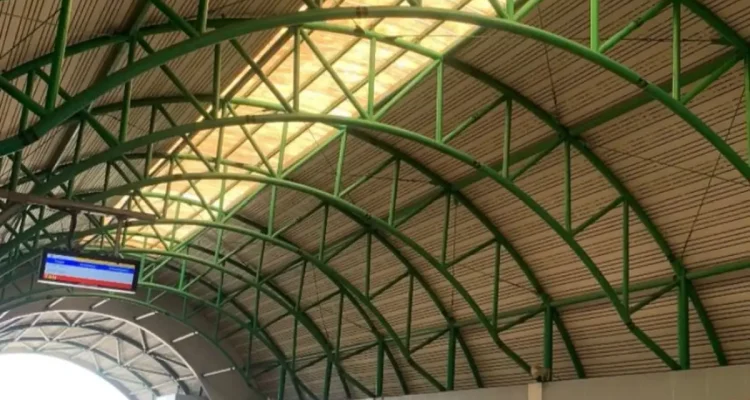 Suasana peron Stasiun LRT Sumsel yang bersih dengan satu unit kereta LRT sedang berhenti di jalur, menampilkan struktur atap melengkung hijau ikonik.
