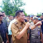 bupati-muba-toha-tohet-audiensi-minyak-rakyat Bupati Musi Banyuasin HM Toha Tohet SH mengenakan seragam dinas cokelat, memegang mikrofon sambil menunjuk ke arah depan saat memberikan arahan tegas di tengah kawalan Satpol PP dan kerumunan warga.