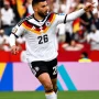 Penyerang Timnas Jerman Denis Undav bernomor punggung 26 sedang berlari melakukan selebrasi sambil menunjuk ke arah tribun penonton setelah mencetak gol.