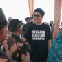 Anggota DPRD Provinsi Sumsel H. Handry Pratama Putra memakai kaos hitam bertuliskan Menapak Berjejak Berdampak sedang berbincang dengan warga di bawah tenda acara.