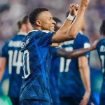 Penyerang Timnas Prancis Kylian Mbappe tersenyum lebar sambil mengepalkan tangan kanannya ke atas merayakan golnya.