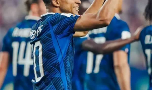 kylian-mbappe-selebrasi-caps-100-piala-dunia Penyerang Timnas Prancis Kylian Mbappe tersenyum lebar sambil mengepalkan tangan kanannya ke atas merayakan golnya.