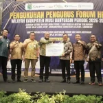 pelantikan-pengurus-forum-hrd-muba-2026 Jajaran pengurus Forum HRD Muba bersama pejabat pemkab dan direksi BPJS Ketenagakerjaan berdiri bersama di atas panggung formal, mengepalkan tangan ke depan sebagai simbol sinergi, sambil memegang maket kartu kepesertaan BPJS berukuran besar.