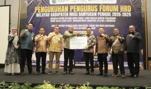 Jajaran pengurus Forum HRD Muba bersama pejabat pemkab dan direksi BPJS Ketenagakerjaan berdiri bersama di atas panggung formal, mengepalkan tangan ke depan sebagai simbol sinergi, sambil memegang maket kartu kepesertaan BPJS berukuran besar.