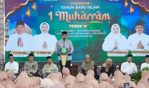 Wakil Bupati Muba Kyai H Abdur Rohman Husen baju koko abu-abu dan peci hitam berbicara di podium berlogo Pemkab Muba. Di belakangnya terdapat layar LED besar bertuliskan Peringatan Tahun Baru Islam 1 Muharram 1448 H beserta foto pimpinan daerah.