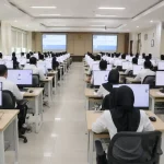 Suasana di dalam ruang laboratorium komputer tempat para peserta berpakaian kemeja putih sedang serius mengikuti ujian Seleksi Kompetensi ASN di depan layar monitor.