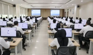 suasana-seleksi-kompetensi-asn-resmi-bkn Suasana di dalam ruang laboratorium komputer tempat para peserta berpakaian kemeja putih sedang serius mengikuti ujian Seleksi Kompetensi ASN di depan layar monitor.