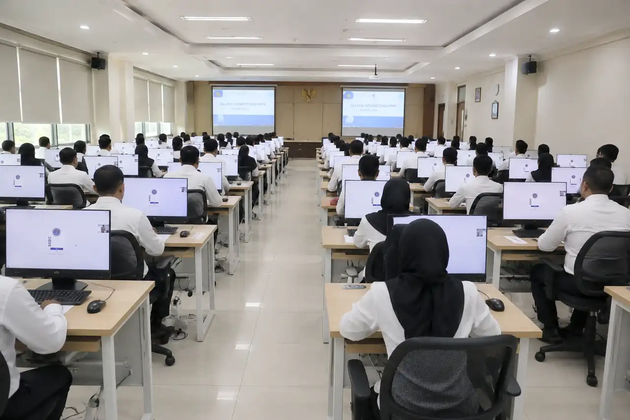 suasana-seleksi-kompetensi-asn-resmi-bkn Suasana di dalam ruang laboratorium komputer tempat para peserta berpakaian kemeja putih sedang serius mengikuti ujian Seleksi Kompetensi ASN di depan layar monitor.