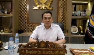 Wakil Ketua DPRD Sumsel H Nopianto duduk di ruang kerjanya dengan latar belakang lambang DPRD dan bendera Partai NasDem.